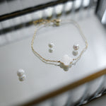 Pearl necklace and earrings on a reflective surface