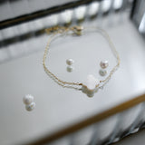 Pearl necklace and earrings on a reflective surface