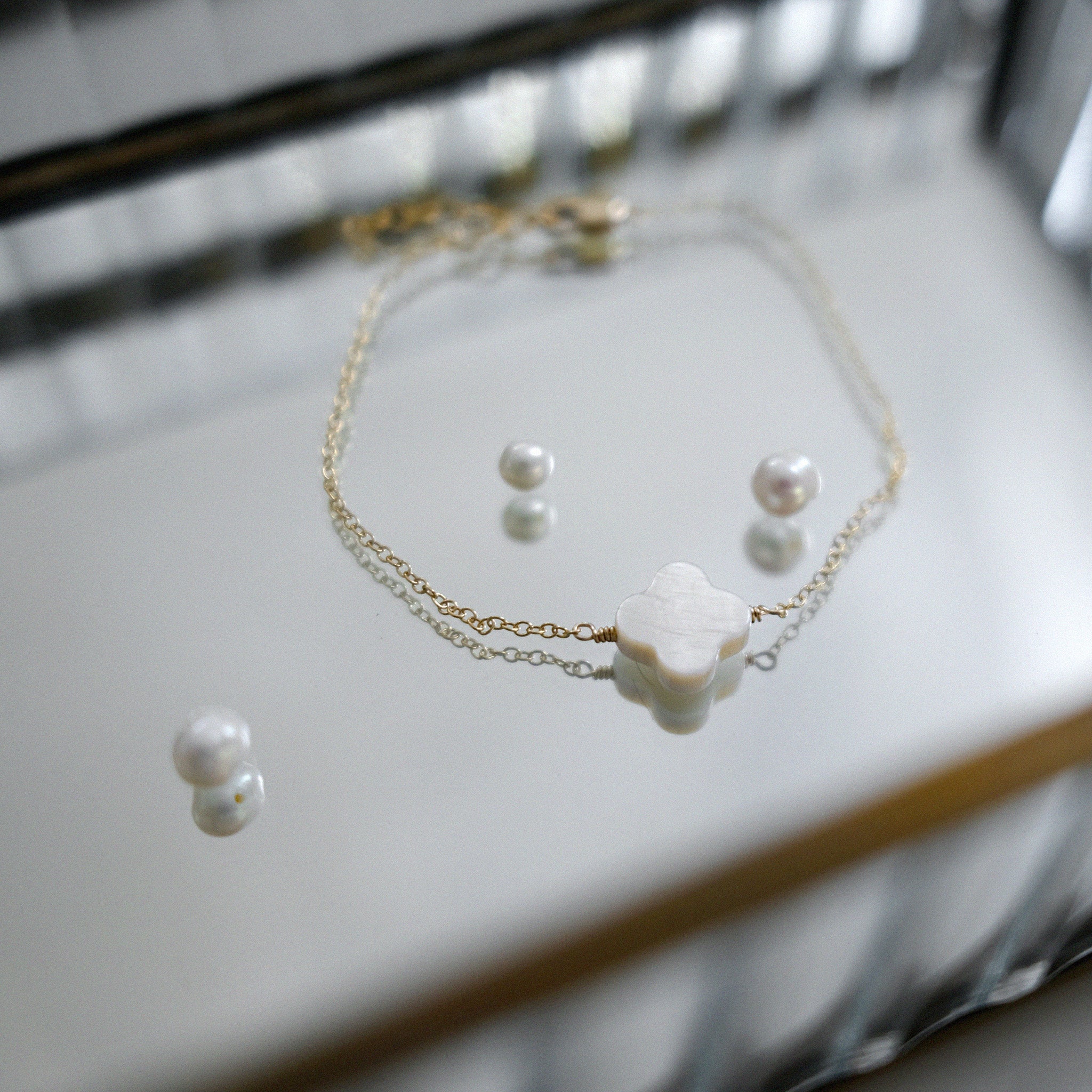 Pearl necklace and earrings on a reflective surface