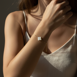 Close-up of a person wearing a delicate bracelet with a clear stone on a dark background