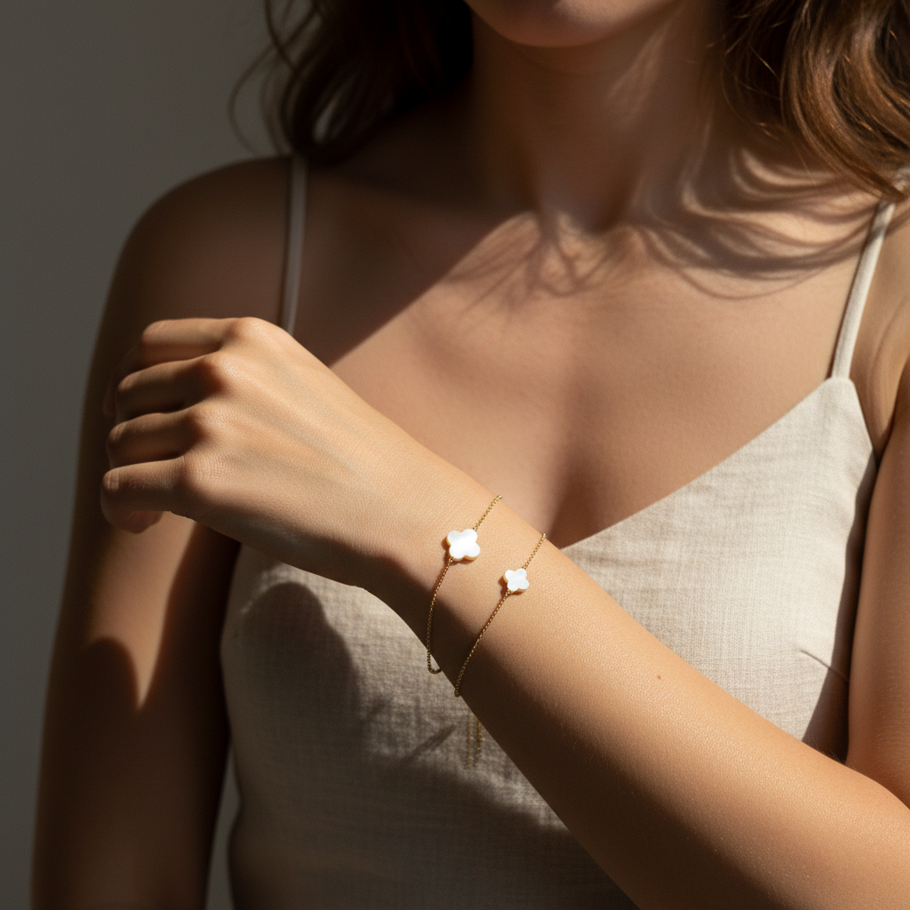 Woman wearing a delicate bracelet with 4-leaf-clover-shaped charms on a neutral background
