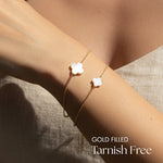 Gold filled bracelet with white clover charms on a wrist, labeled 'Tarnish Free'.