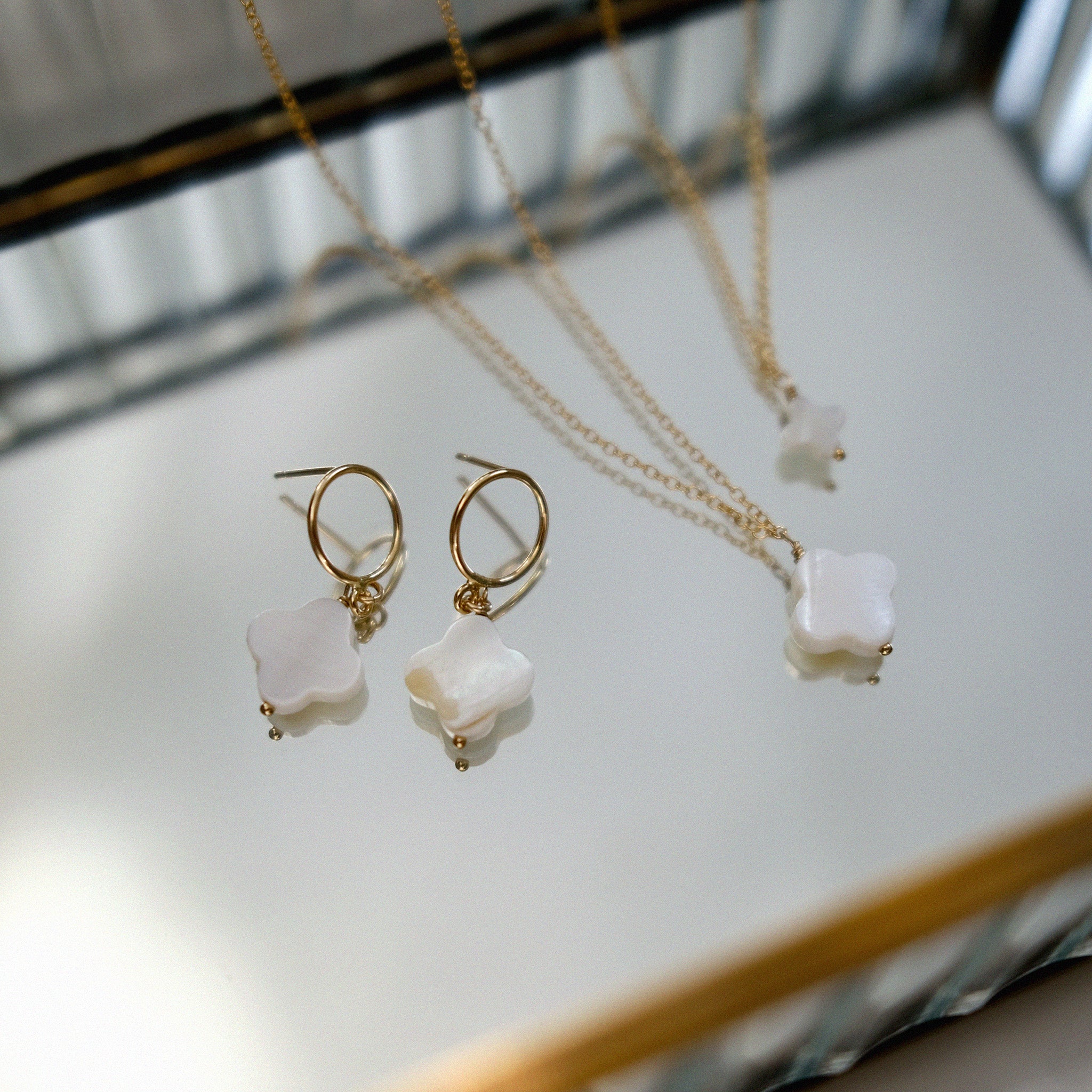 Gold jewelry set with mothe of clove charm on a light surface