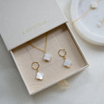 Jewelry set with gold necklaces and earrings in a 'LAONDRIM' box on a light background