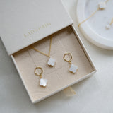 Jewelry set with gold necklaces and earrings in a 'LAONDRIM' box on a light background