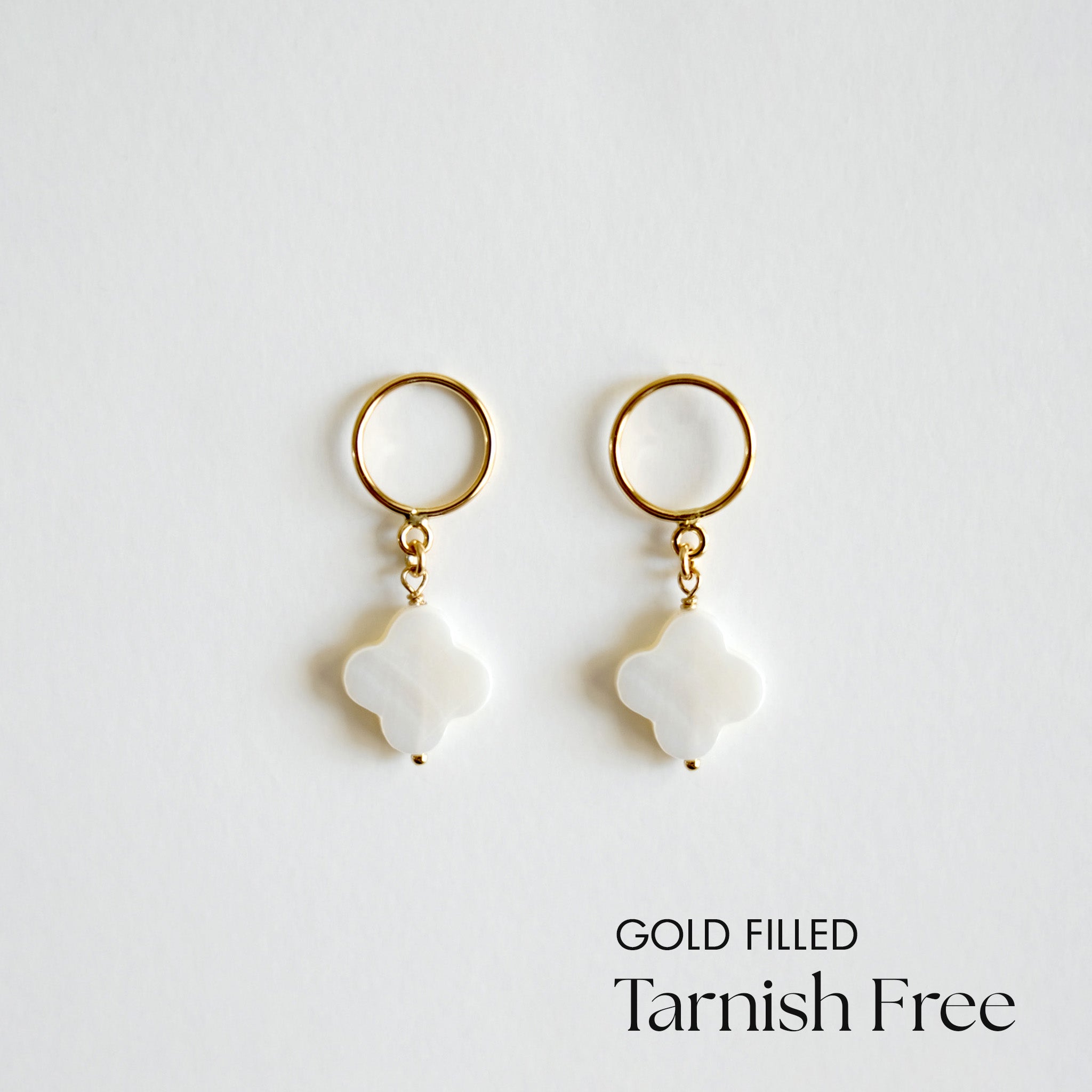 Gold-filled clover pendant earrings on a light gray background