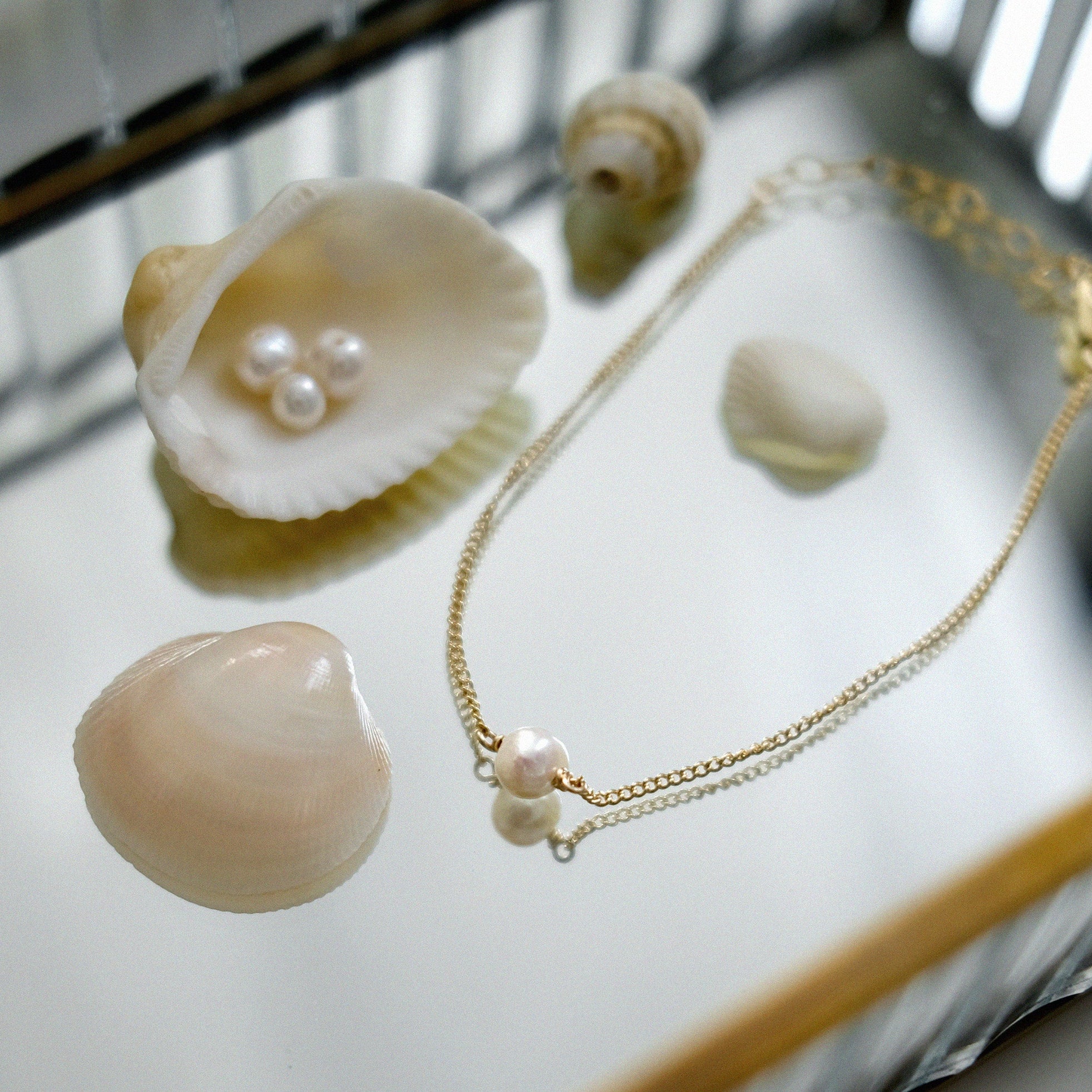 Pearl bracelet with shells on a reflective surface