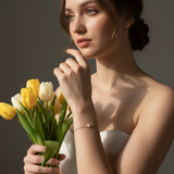 Woman holding a bouquet of yellow and white tulips against a neutral background