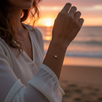Person wearing a pearl bracelet on a beach at sunset