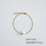 Gold-filled bracelet with a pearl on a light gray background