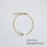 Gold-filled bracelet with a pearl on a light gray background