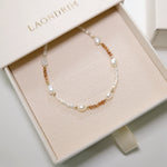 Pearl and gold beaded bracelet in a 'LAONDRIM' box on a light background