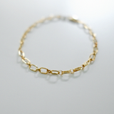 Gold chain bracelet on a light gray background