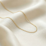 Gold chain necklace on a beige fabric background