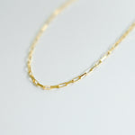 Gold chain necklace on a light gray background