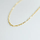 Gold chain necklace on a light gray background