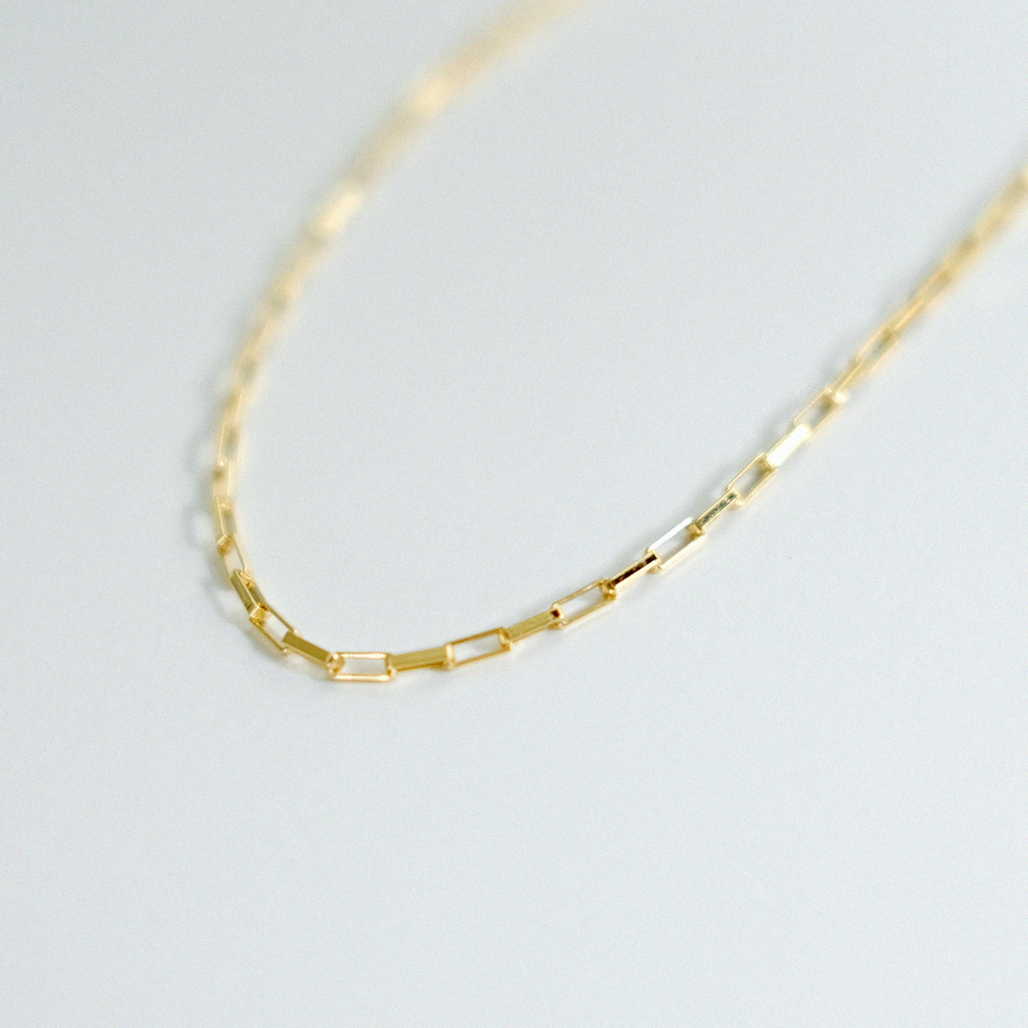 Gold chain necklace on a light gray background