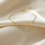 Gold chain necklace on a soft beige fabric background