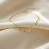 Gold chain necklace on a soft beige fabric background