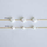 Two gold bracelets with white beads on a light gray background, labeled '10mm' and '6mm'.