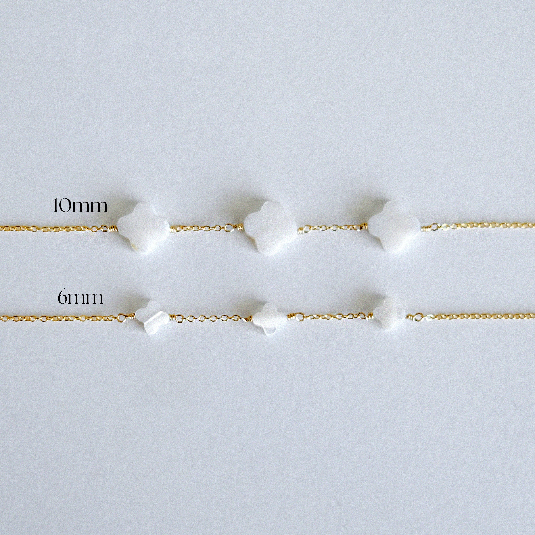 Two gold bracelets with white beads on a light gray background, labeled '10mm' and '6mm'.
