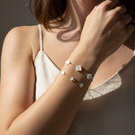 Close-up of a person wearing a delicate bracelet with floral designs on a neutral background