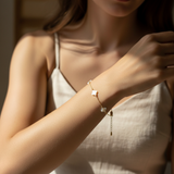 Woman wearing a delicate bracelet with small four leaf clover charm on a blurred background
