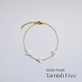 Gold-filled bracelet with white stones on a light gray background