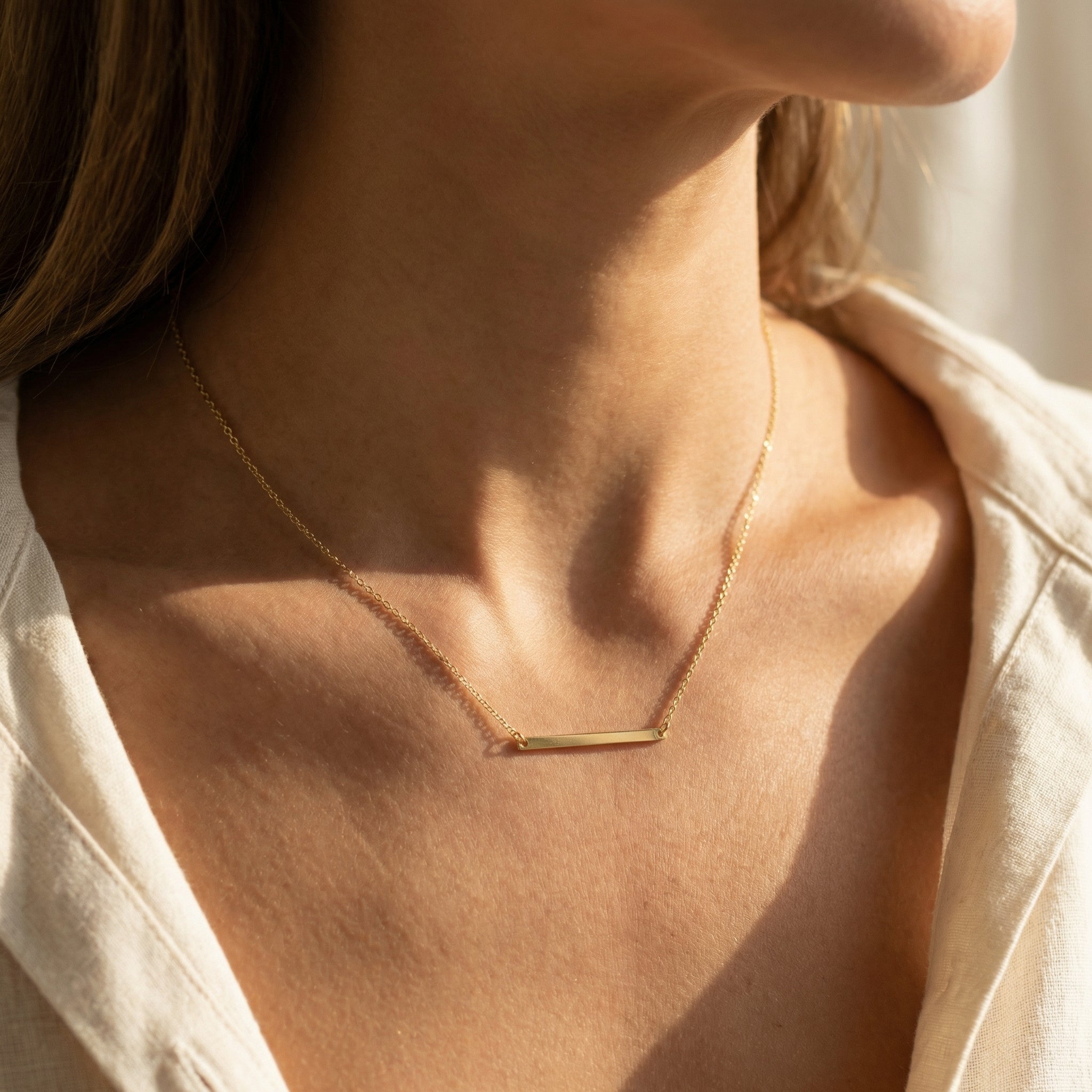Gold necklace on a person wearing a light-colored shirt