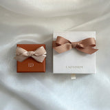Two gift boxes with ribbons on a textured white surface, featuring the brand 'LAONDRIM'.