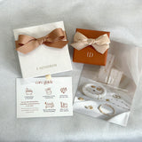 Jewelry set with branded box, care guide, and product images on a light gray background