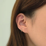 14K gold huggie earring featuring dainty clover charm styled on upper ear