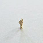 Front-facing view of huggie hoop earring with cubic zirconia clover accent