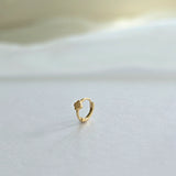 Close-up of clover-accented gold hoop earring shown from side profile
