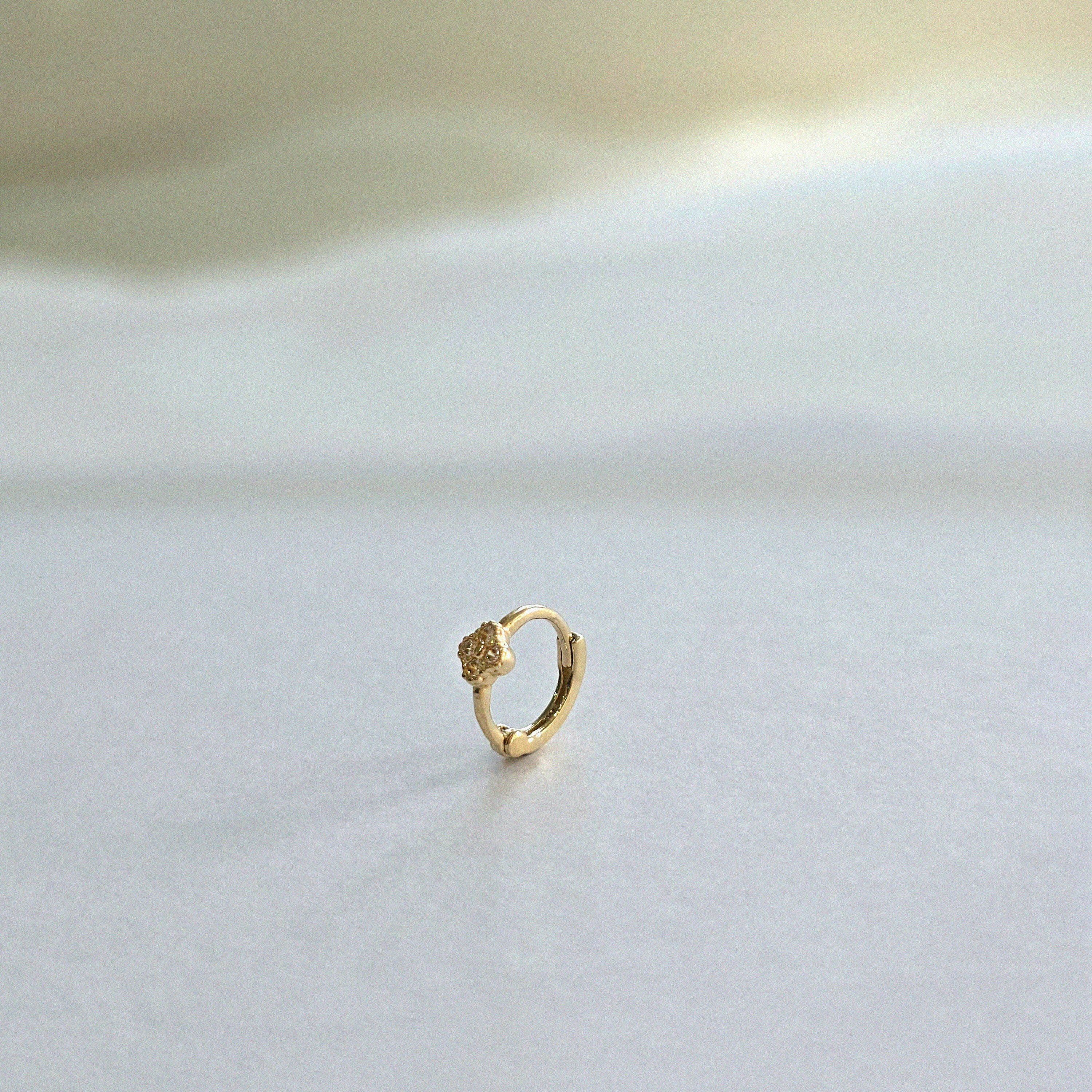 Close-up of clover-accented gold hoop earring shown from side profile