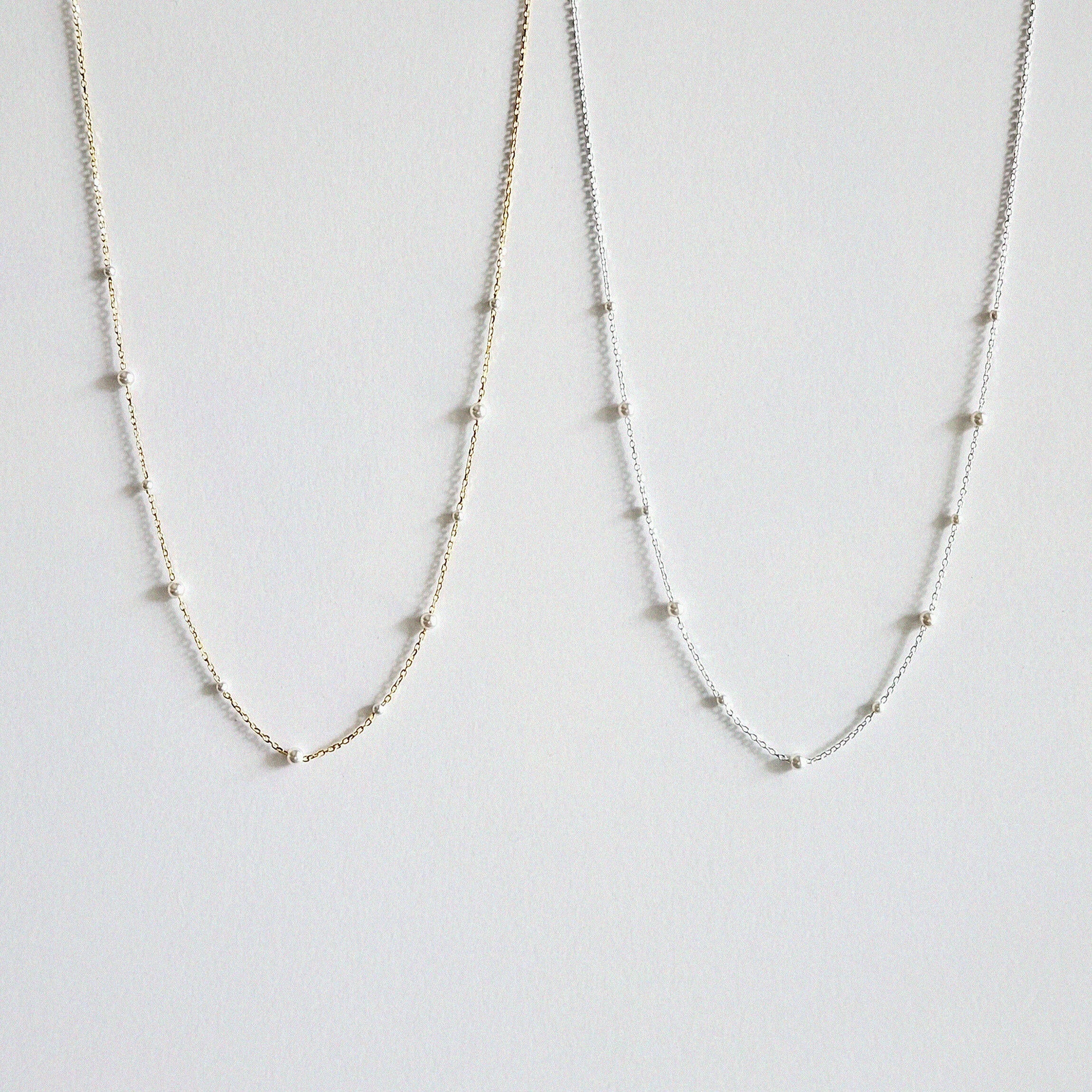 Gold and silver pearl necklaces side by side featuring subtle size variations