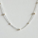 Zoomed-in view capturing pearl surface and silver chain texture with soft shine