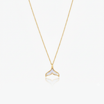 Gold necklace with a whale tail pendant on a white background