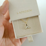 Gold and white pendant necklace in a 'LAONDRIM' box held by a hand.