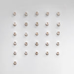 Mother of pearl initial charms spelling out 'ABCDEFGHIJKLMNOPQRSTUVWXYZ' on a light gray background