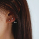 Model wearing 3mm and 2mm cubic zirconia studs on earlobe for size comparison.