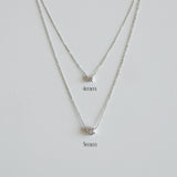 Silver necklace with two different chain widths on a light gray background