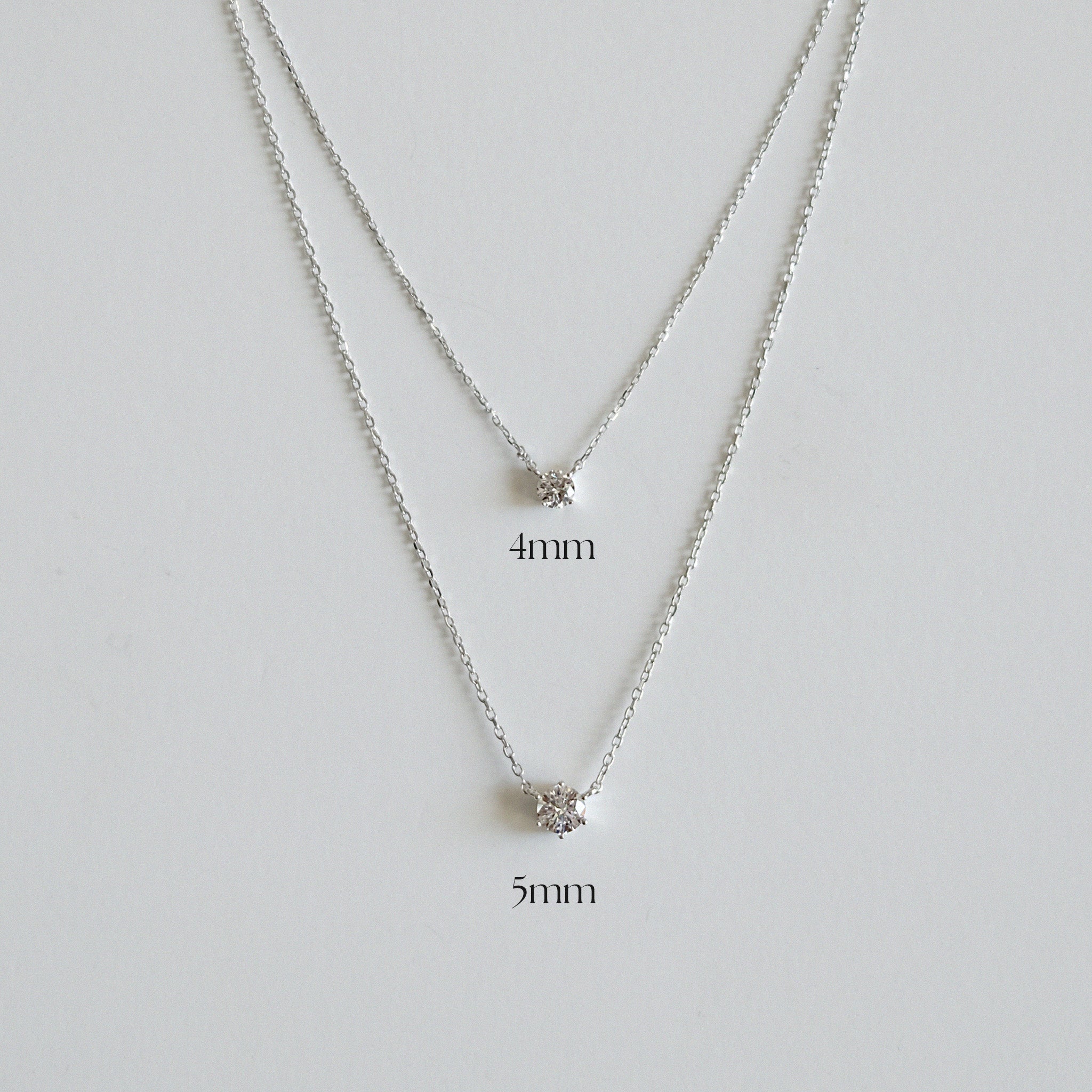 Silver necklace with two different chain widths on a light gray background