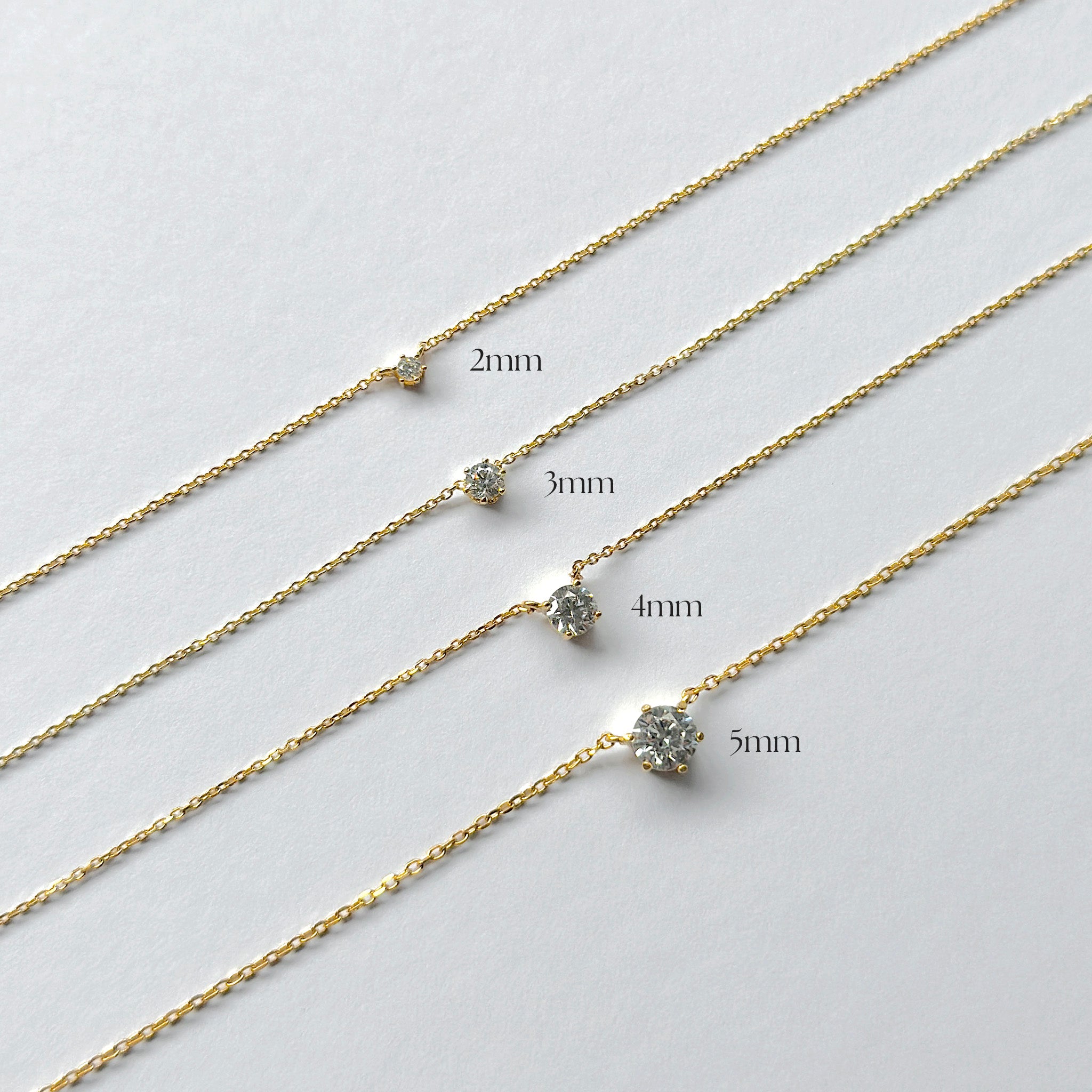 Gold chain necklace with varying width labels on a light gray background