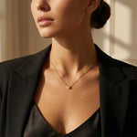 Woman wearing a gold necklace with a small pendant against a neutral background