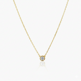 Gold necklace with a small round diamond pendant on a white background