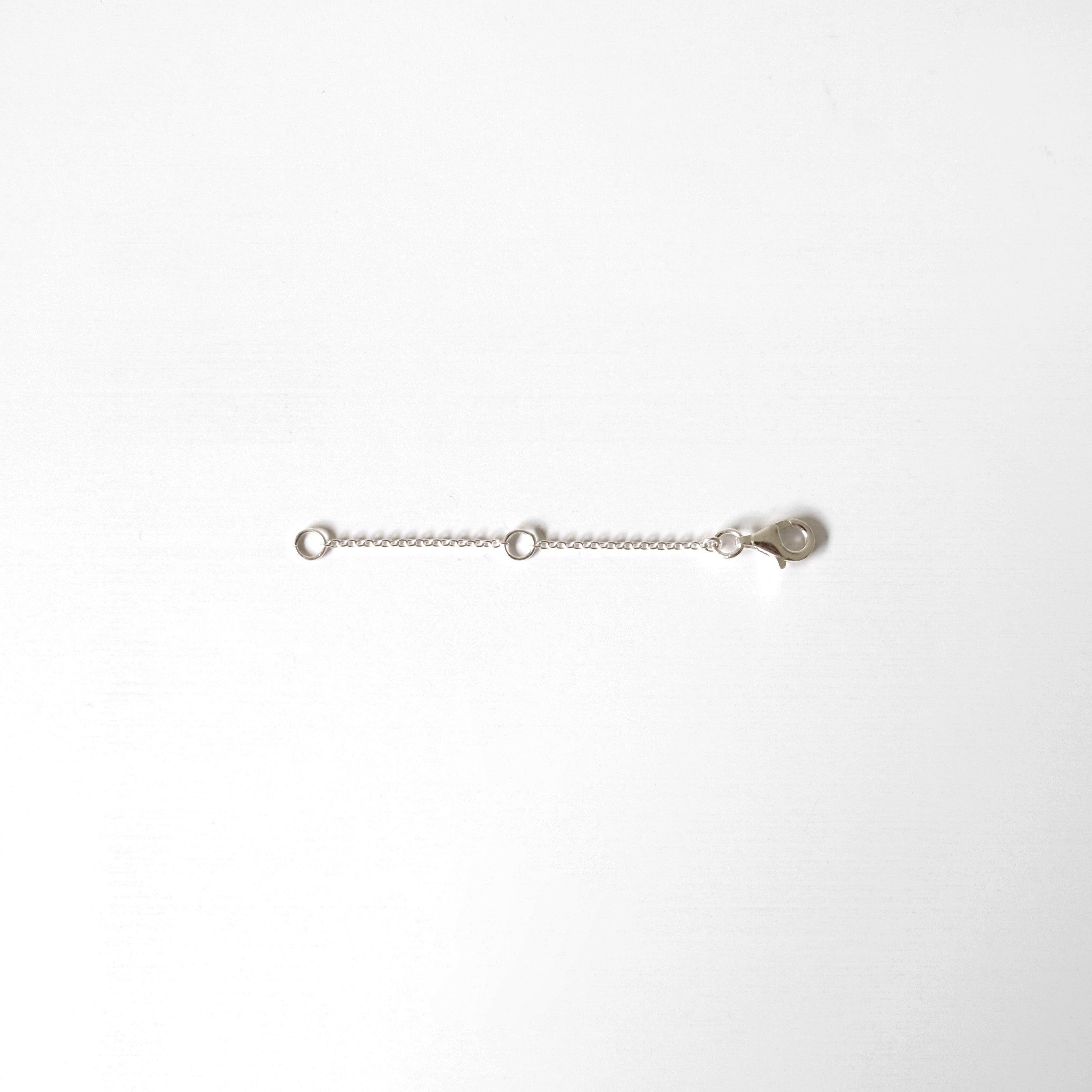Sterling silver and gold chain extenders laid flat on white background with lobster clasps and O-rings visible