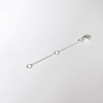 Macro shot of lobster clasp and O-ring connection on silver chain extender.