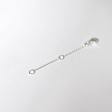 Macro shot of lobster clasp and O-ring connection on silver chain extender.