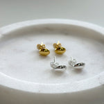 Gold and silver Teardrop-shaped earrings on a white plate